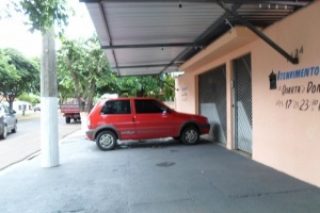 Um Fiat Uno estacionado na calçada em frente a garagem de uma casa, atrapalhando o trânsito de pedestres.